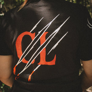 Person wearing a black t-shirt with orange and white design outdoors