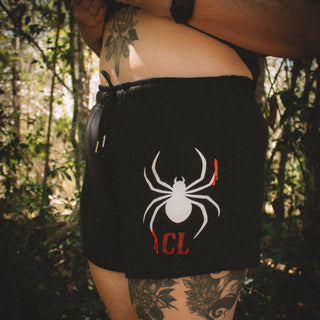 Person wearing a black outfit with a spider design in a forest setting