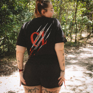 Person wearing a black t-shirt with red and white design in a forest setting