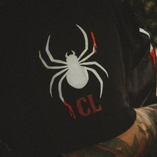 Black hoodie with a white spider design and 'CL' letters on a dark background